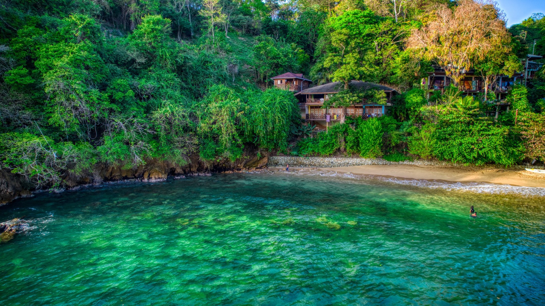 Türkisfarbene Bucht mit Pension zwischen Regenwald auf Tobago