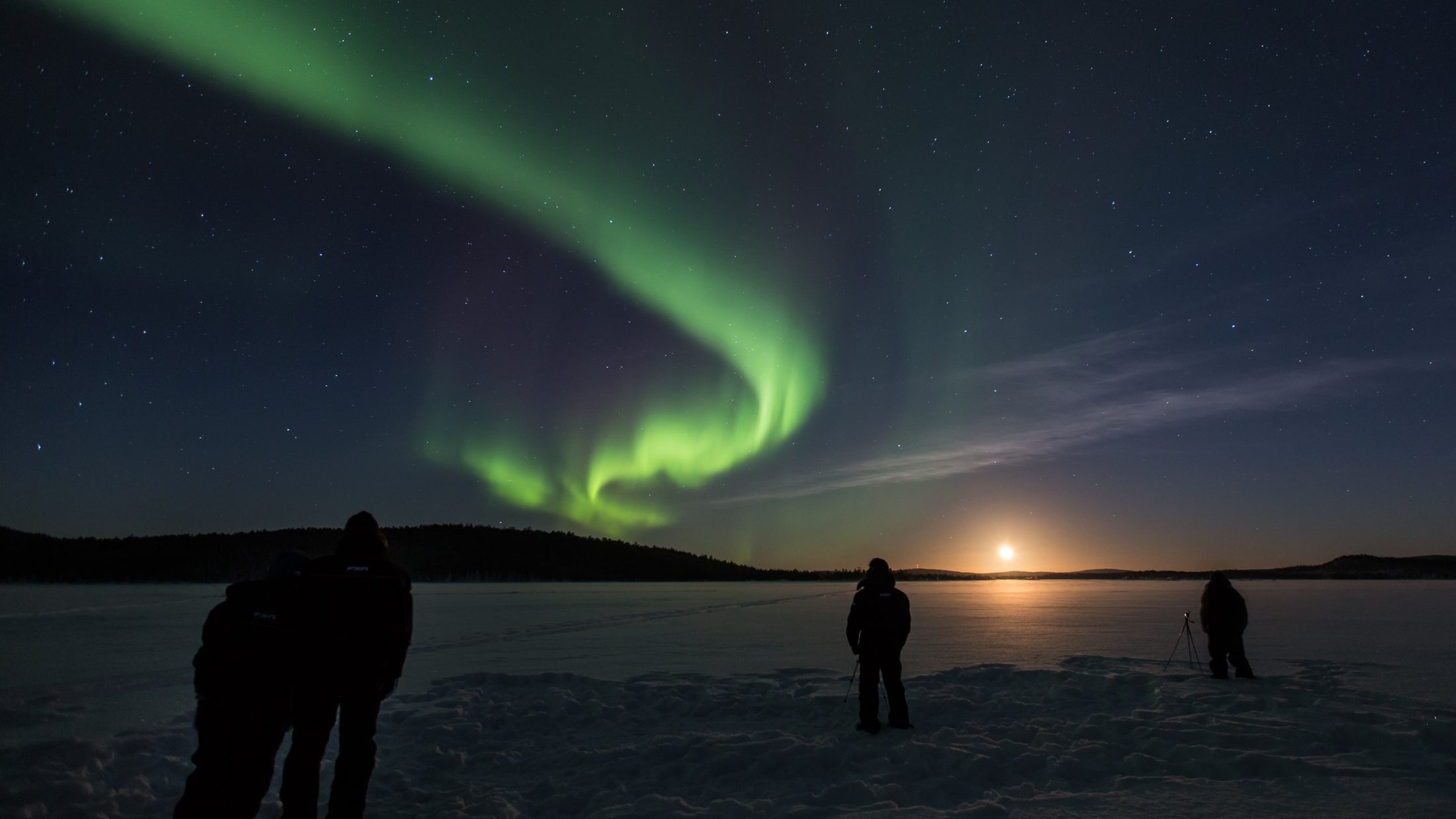 Fotografen beobachten die Aurora Borealis über einem zugefrorenen See in Finnisch-Lappland